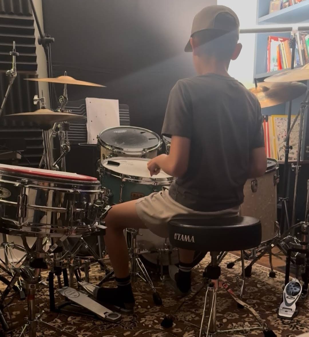 Drum student wearing cap, playing kit
