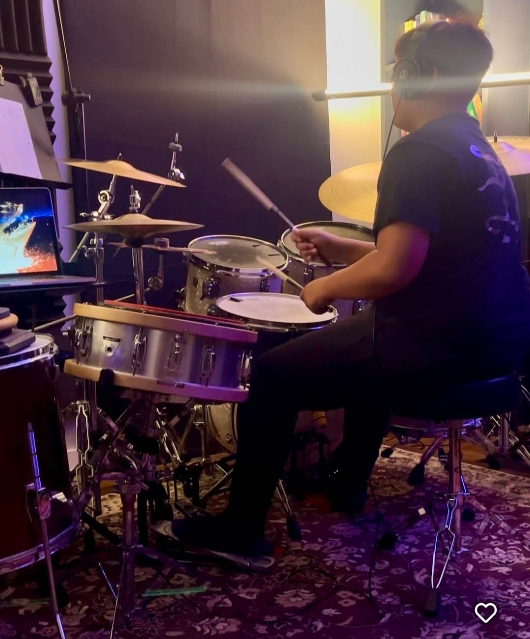 Drum student with headphones in purple lighting
